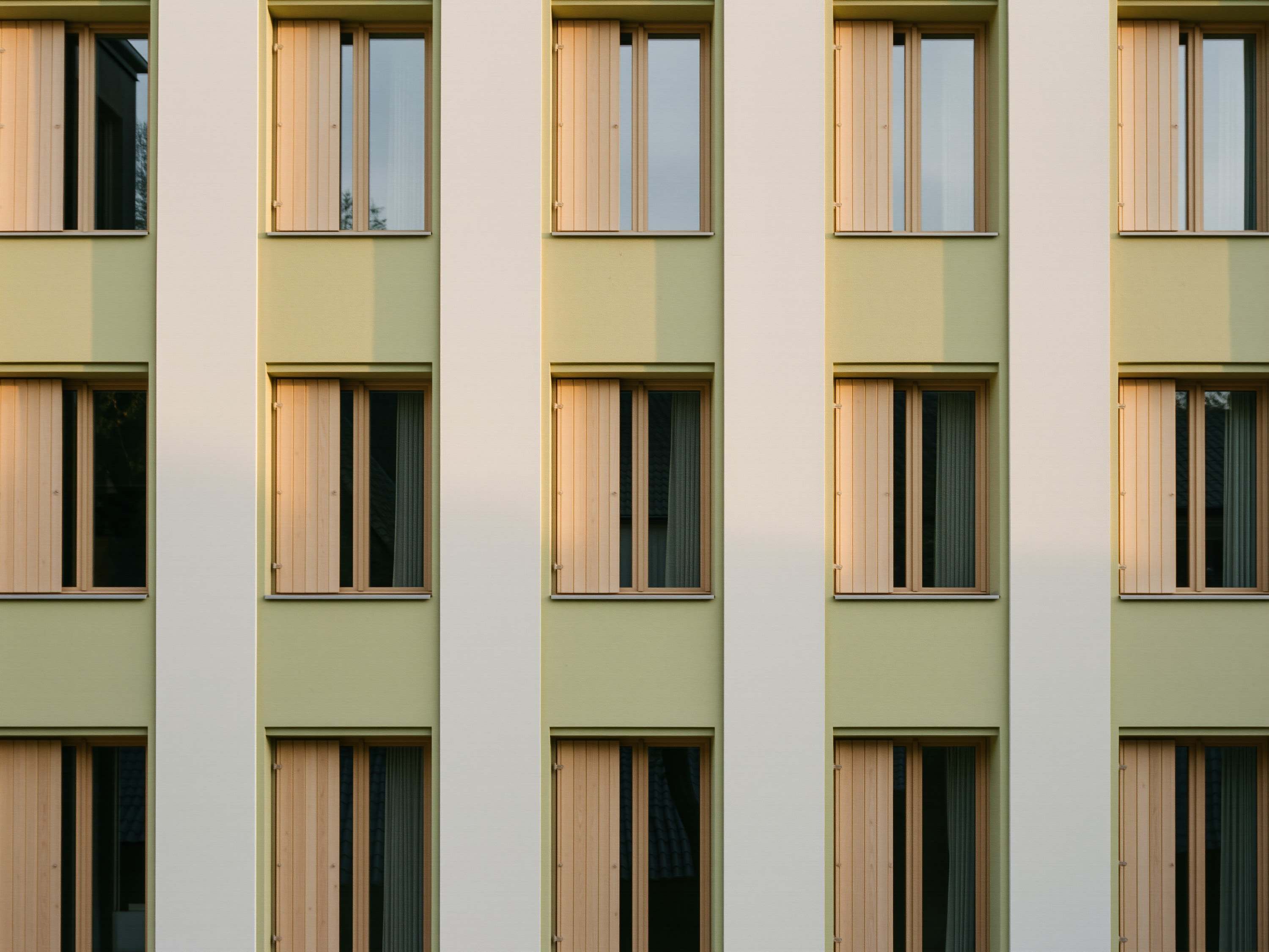 Wohnhausfassade mit regelmäßigen Fensteröffnungen und Holzläden